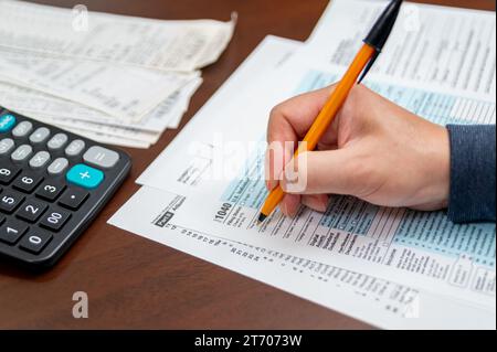 Ein Mann, der die Einkommensteuererklärung 1040 und die Quittungen organisiert. Unscharfer Hintergrund. Steuerzeit.Steuerkonzept. Nahaufnahme. Stockfoto