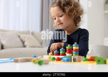 Entwicklung der motorischen Fähigkeiten. Ein kleines Mädchen, das im Haus mit Stapel- und Zählspiel spielt Stockfoto