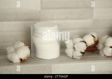 Wattepads und Blumen auf gekachelter Oberfläche in Innenräumen Stockfoto