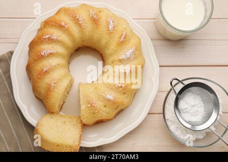Leckerer Biskuitkuchen mit Puderzucker und einem Glas Milch auf Holztisch, flach gelegt Stockfoto
