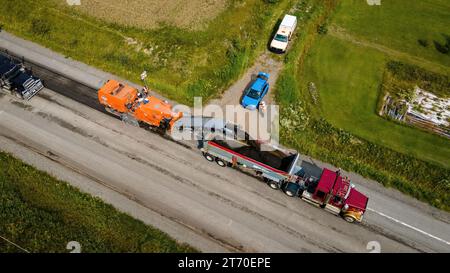 21. August 2023, Macamic, Quebec, Kanada; Luftaufnahme eines Asphalthobels und eines Kipplagers auf einer Straßenbaustelle, mit Aufsichtspersonen Stockfoto