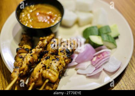 Satay-Hühnerspieße mit roten Zwiebeln, Gurkenscheiben, Reiskuchen und Erdnussdippsoße im Limapulo: Baba Cook, ein Peranakan-Restaurant Stockfoto