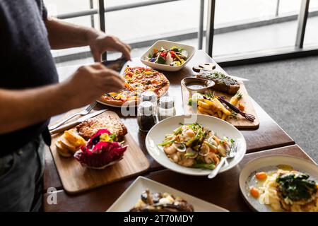 Mann, der Fotos von leckeren italienischen Gerichten auf dem Restauranttisch macht. Stockfoto