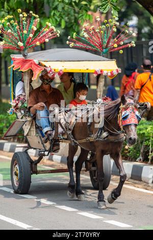 Jakarta, Indonesien - 11. November 2023: Nicht identifizierte Menschen, die mit einer Pferdekutsche auf den Straßen von Jakarta fahren. Stockfoto