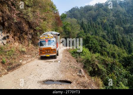 Lastwagen beladen mit Gütern, die entlang einer gefährlichen Bergstraße mit Schlaglöchern in der Nähe von Kolakham im Bezirk Kalimpong, Indien, fahren. Stockfoto