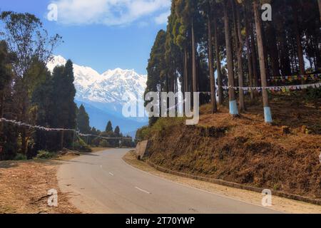 Malerische Bergstraße mit Blick auf die majestätische schneebedeckte Kanchenjunga Himalaya Bergkette bei Tinchuley, Darjeeling, Indien Stockfoto