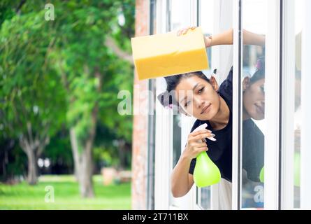 Eine junge Frau wäscht die Außenfenster in einem Haus Stockfoto