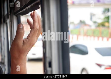 Die Hand des Beifahrers im Fenster eines Stadtbusses, der langsam in einem Stau fährt Stockfoto