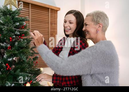 Tochter und Mutter kaukasier schmücken den Weihnachtsbaum, um sich auf den Weihnachtsfeiertag der Familie vorzubereiten Stockfoto