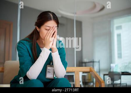 Müde junge medizinische Krankenschwester weint im Krankenhaus-Loungebereich nach einem anstrengenden Arbeitstag Stockfoto