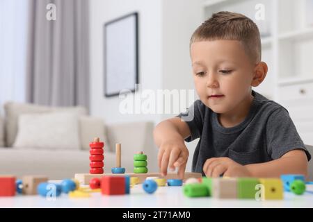 Entwicklung der motorischen Fähigkeiten. Kleiner Junge, der drinnen mit Stapel- und Zählspiel spielt Stockfoto