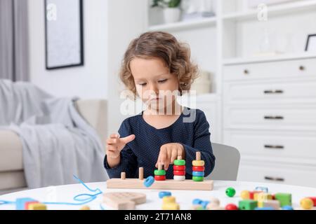 Entwicklung der motorischen Fähigkeiten. Ein kleines Mädchen, das im Haus mit Stapel- und Zählspiel spielt Stockfoto