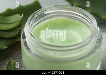 Glas mit Creme und geschnittenen Aloe-Blättern auf dem Tisch, Nahaufnahme Stockfoto