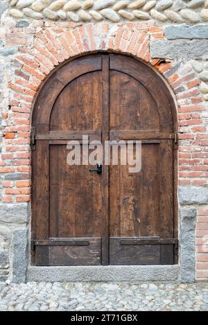 Italien, Rezept von Candelo. Panorama des mittelalterlichen Dorfes. Geschichte und Kultur Italiens und Europas. Isolierte Holztür im Vordergrund. Stockfoto