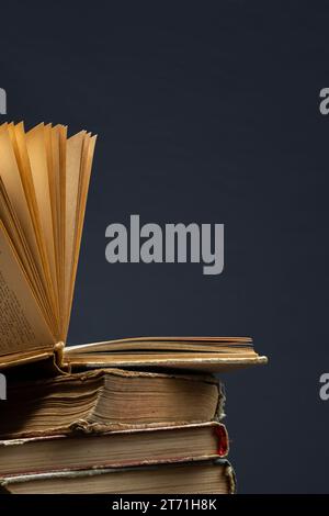 Ein Stapel alter Bücher mit einem geöffneten Buch oben auf dunklem Hintergrund. Alte Bücher in der Bibliothek. Bücherregal-Laden. Wissensveröffentlichungen, Literatur. Buchmacher bo Stockfoto