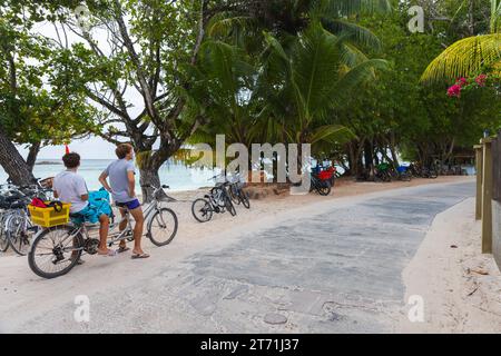 La Digue, Seychellen - 16. August 2023: Anse strenger Blick auf den Strand mit Touristen auf Fahrrädern Stockfoto