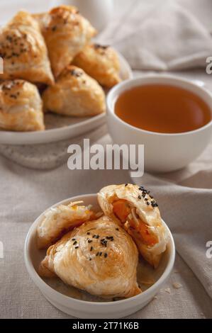 Pustet heiße samsa mit Kürbis und heißem Tee. Tischaufstellung im europäischen Stil. Stockfoto