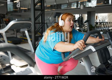 Porträt einer motivierten übergewichtigen Frau, die im Fitnessstudio Fahrrad fährt Stockfoto