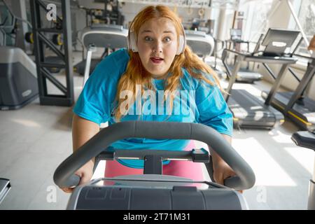 Porträt einer motivierten übergewichtigen Frau, die im Fitnessstudio Fahrrad fährt Stockfoto