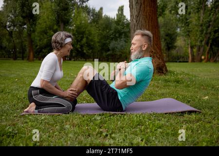 Glückliche verheiratete Rentner, die im Park trainieren Stockfoto