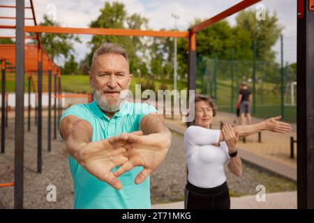 Senioren verbinden sich mit ausstreckenden Armen, bevor sie auf dem Trainingsfeld im Freien trainieren Stockfoto