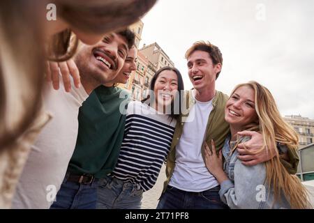 Multirassische junge Leute, die sich im Freien umarmen, verschiedene Studenten und Freunde, die glücklich lachen. Stockfoto