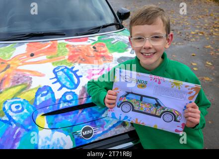 Der Gewinner des Wettbewerbs, Oliver Gorrod, 9 Jahre alt von Didcot Pose mit einem MINI Electric, der seine „MINI-Köpfe“ zeigt... Mit Crayolas erfolgreichem Design, wie es an seiner Schule vorgestellt wird, Sutton Courtenay C von der E Primary School in Abingdon, Oxfordshire. Ausgabedatum: Montag, 13. November 2023. Stockfoto