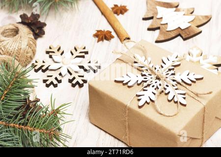 Weihnachten Hintergrund mit geschenkboxen in braunes Packpapier eingewickelt, Tannenbaum Äste, Tannenzapfen, Zimtstangen und Sterne Anis auf weißem Holz- Hintergrund Stockfoto