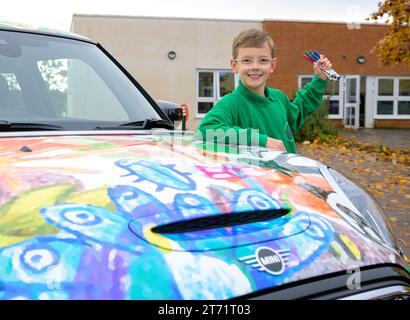 Der Gewinner des Wettbewerbs, Oliver Gorrod, 9 Jahre alt von Didcot Pose mit einem MINI Electric, der seine „MINI-Köpfe“ zeigt... Mit Crayolas erfolgreichem Design, wie es an seiner Schule vorgestellt wird, Sutton Courtenay C von der E Primary School in Abingdon, Oxfordshire. Ausgabedatum: Montag, 13. November 2023. Stockfoto