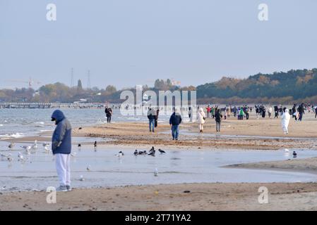 Menschen mit Jacken, die bei kaltem Wetter am Strand von Danzig, Polen, Europa, EU spazieren gehen Stockfoto