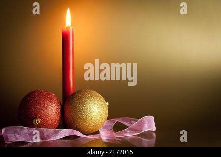 weihnachtskugeln mit roter Kerze auf goldenem Hintergrund; weihnachtskugeln mit roter Kerze auf goldenem Hintergrund Stockfoto