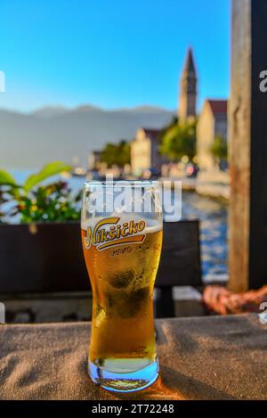 Staunten Sie über die Schönheit des goldenen Sonnenuntergangs in den Buchten von Kotor und Risano bei einem Pint Nikšićko Gold im Hotel Admiral in Perast, Montenegro Stockfoto