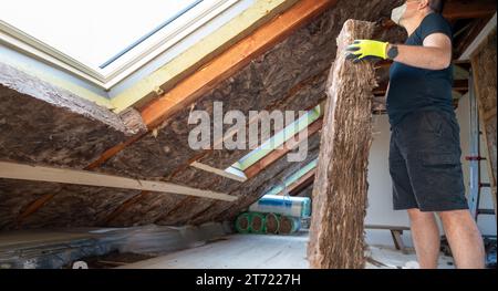 Der Handwerker hält Isoliermaterial, um den Dachboden zu isolieren. Stockfoto