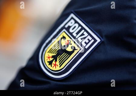 München, Deutschland. November 2023. Das nationale Emblem der Bundespolizei, ein Wappen mit dem Wort Polizei und einem Adler, ist auf dem Ärmel der Uniform eines Bundespolizisten zu sehen. Quelle: Matthias Balk/dpa/Alamy Live News Stockfoto