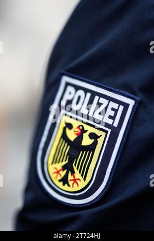 München, Deutschland. November 2023. Das nationale Emblem der Bundespolizei, ein Wappen mit dem Wort Polizei und einem Adler, ist auf dem Ärmel der Uniform eines Bundespolizisten zu sehen. Quelle: Matthias Balk/dpa/Alamy Live News Stockfoto