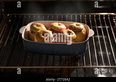 Dämpfen gebackener Äpfel im Ofen, gefüllt mit Mandeln, Honig und Zimt, Vorbereitung auf ein Weihnachtsdessert an Thanksgiving, Weihnachten oder Neujahr, Stockfoto