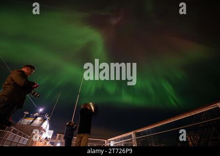 Mehrere Menschen werden während einer aurora Borellae-Erscheinung am Himmel in der Nähe von Bøøyna, Norwegen, fotografiert. Nordlichter sind natürliche Phänomene, die den Nachthimmel in den Polarregionen beleuchten. Sie entstehen durch die Interaktion geladener Sonnenpartikel mit der Erdatmosphäre und erzeugen farbenfrohe, tanzende Lichtblitze in Grün-, Rosa- und Violetttönen. Dieses himmlische Spektakel ist das Ergebnis der Anregung von Atomen und Molekülen in der oberen Atmosphäre und erzeugt einen optisch beeindruckenden Effekt. Quelle: SOPA Images Limited/Alamy Live News Stockfoto