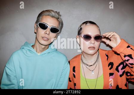 Porträt von zwei kreativen jungen Paaren, die eine Sonnenbrille tragen und mit Blitz posieren Stockfoto