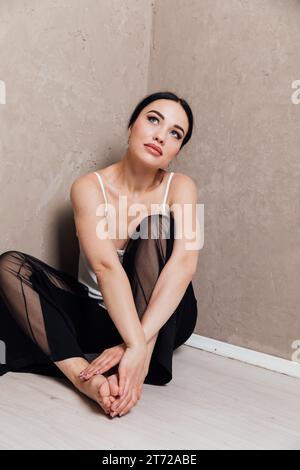 Eine brütende Frau in schwarzer Hose sitzt in einer Ecke Stockfoto