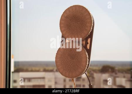 Ein moderner Staubsauger-Fensterreiniger reinigt Glas von Schmutz und Flecken auf einem pvc-Balkonrahmen. Sturzsicherheit. Stockfoto