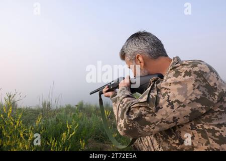 Mann, der Tarnung trägt und mit Jagdgewehr im Freien zielt. Leerzeichen für Text Stockfoto