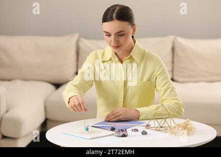 Astrologe mit Pendel und Tierkreisrad für die Schicksalsprognose am Tisch drinnen. Glücksbringer Stockfoto