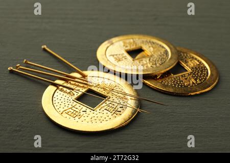 Akupunkturnadeln und antike chinesische Münzen auf grauem Holztisch, Nahaufnahme Stockfoto