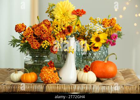 Schöne Herbstkomposition mit Kürbissen und Blumen auf Korbtisch Stockfoto