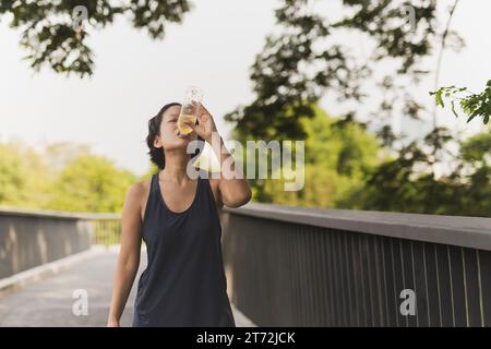 Frau trinkt Energie-Drink, nachdem sie im Park gelaufen ist. Stockfoto