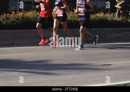 Izmir, Türkei, 10. September 2023: In einer dynamischen Nahaufnahme werden die Schritte und sportlichen Schuhe von drei Marathonläufern festgehalten, mit einer Frau und zwei Stockfoto