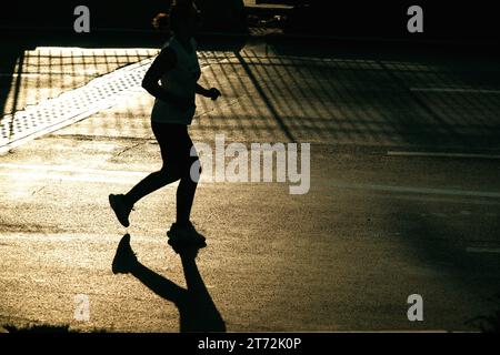 Izmir, Türkei, 10. September 2023: Läufer werden während des Izmir-Marathons zu Silhouetten gegen das helle Sonnenlicht auf dem Asphalt Stockfoto