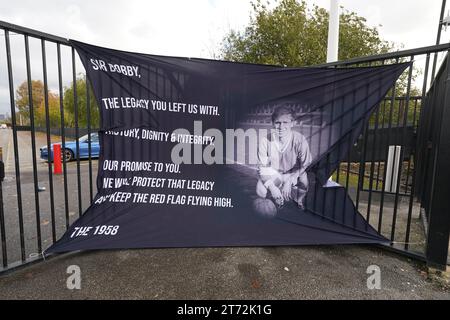 Ein Tribut-Banner an einem Tor vor Old Trafford in Manchester vor der Trauerprozession für den britischen Sir Bobby Charlton, der im Oktober im Alter von 86 Jahren starb. Charlton erzielte 249 Tore für Manchester United und half ihnen, drei Meistertitel, einen FA Cup und den Europapokal 1968 zu gewinnen. Auf internationaler Ebene war er Teil der englischen Mannschaft, die 1966 die Weltmeisterschaft gewann. Bilddatum: Montag, 13. November 2023. Stockfoto