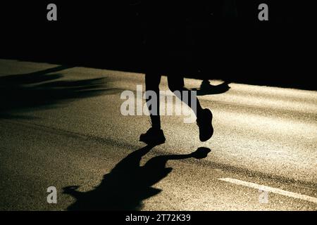 Izmir, Türkei, 10. September 2023: Läufer werden während des Izmir-Marathons zu Silhouetten gegen das helle Sonnenlicht auf dem Asphalt Stockfoto