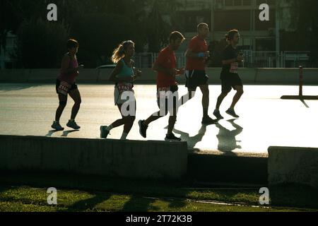 Izmir, Türkei, 10. September 2023: Läufer werden während des Izmir-Marathons zu Silhouetten gegen das helle Sonnenlicht auf dem Asphalt Stockfoto